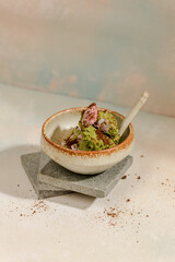 a combination of strawberry ice cream and matcha ice cream with a sprinkling of brown sugar in a bowl with an aesthetic stone motif in the art of photography