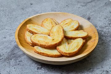 Close up view of many mini pies on wooden plate isolated on grey or gray cement background. Love sign. Heart. Danish. Pastry. Butter.