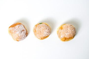 Top view of three bomboloni doughnut with strawberry, pineapple and matcha filling isolated on white background. clipping path. homemade. Italian stuffed donuts. close up.  high angle. above.