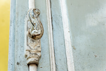 Close-up of an ornate hook latch on a weathered metal window. Ideal for rustic detail shots, heritage textures, or vintage decor.