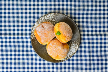 Top view of three bomboloni doughnut with strawberry, pineapple and matcha filling on black And white plate. homemade. Italian stuffed donuts. close up. Isolated on napkin background.