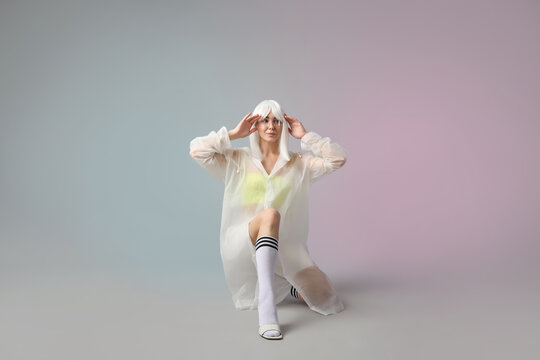 Young woman in futuristic costume with VR glasses on grey background