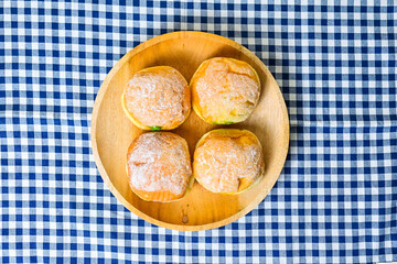 Top view of four bomboloni doughnut with strawberry, pineapple and matcha filling on wooden plate. homemade. Italian stuffed donuts. close up. Isolated on napkin background. High angle. Above.