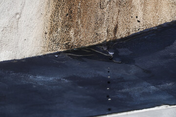 A few drops of water from the wet wall, the path of the water flow leaves a brownish trail on the white wall at the top