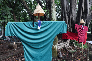 Two scarecrow symbols placed in a public park, the symbol of this scarecrow is wearing a traditional rice cooker as its head and a t-shirt as its body