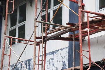 Several scaffolds installed in front of a building were photographed close up, some wood and bamboo were installed between the scaffolds which were useful as footholds for the construction workers