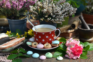 Cozy still life with cup of tea, open diary and sweets with flowers on the table. Romantic, vintage home and greeting card concept