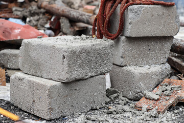 Several white bricks are stacked among the fragments and chunks of the remaining building, a red rope made of cloth is visible on top of the bricks
