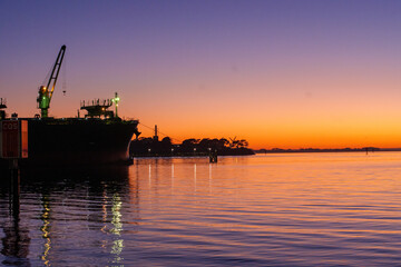 Obraz premium Ferry dock in Geelong for the Spirit of Tasmania with industrial cranes in the background as the sun sets over the Bass Strait in Victoria, Australia