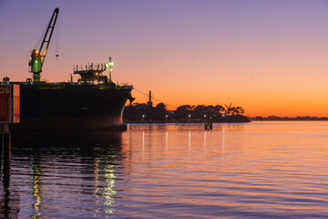 Obraz premium Ferry dock in Geelong for the Spirit of Tasmania with industrial cranes in the background as the sun sets over the Bass Strait in Victoria, Australia