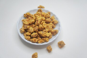 Close-up of egg bean snack (Camilan kacang Telur,Kacang Medan) in a small white plate on a white background. High angle view