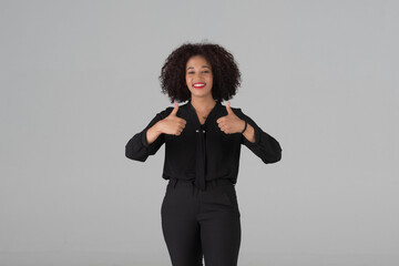 half-body headshot of a beautiful African woman offering a clear thumbs up gesture, perfect for conveying positive feedback or satisfaction studio on gray background.