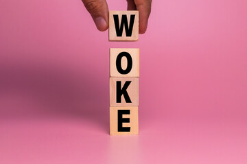 male hand put wooden blocks with woke word symbol isolated on pink background