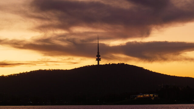 Telstra tower in Canberra, Australia as the sun sets with clouds behind Black Mountain