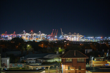 Fototapeta premium Cranes above the Melbourne sky line with Footscray Train Station in the foreground at night photographed in June 2025 from a nearby car park