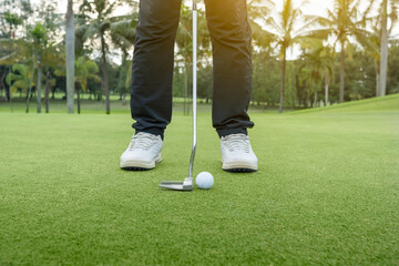 Golfer with a golf club is ready to hit a golf ball on the green grass of a golf course. Concept of...