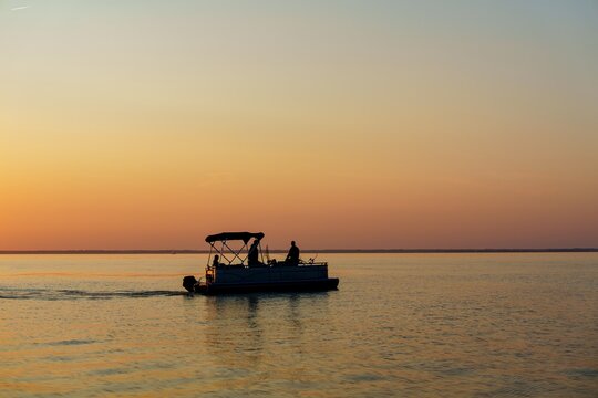 A tranquil sunset fishing scene on the Baltic Sea, featuring a silhouetted pontoon boat against vibrant dusk colors. Perfect for showcasing fishing adventures and relaxing coastal getaways.