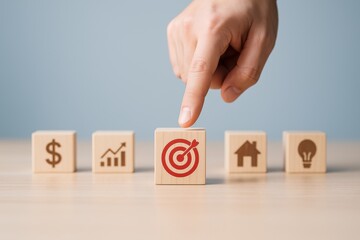 Target Selection in Planning: A human finger thoughtfully selects a target icon amidst a row of wooden blocks, signifying focused goal setting, planning, and strategic choices.