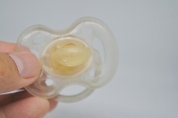 hand holding broken pacifier on white background