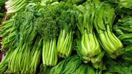 Obraz premium A vibrant collection of fresh leafy greens is arranged neatly at a local market. Customers explore the variety, enjoying the unique textures and colors under natural light.
