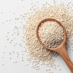 Wooden spoon filled with quinoa seeds scattered on a white surface