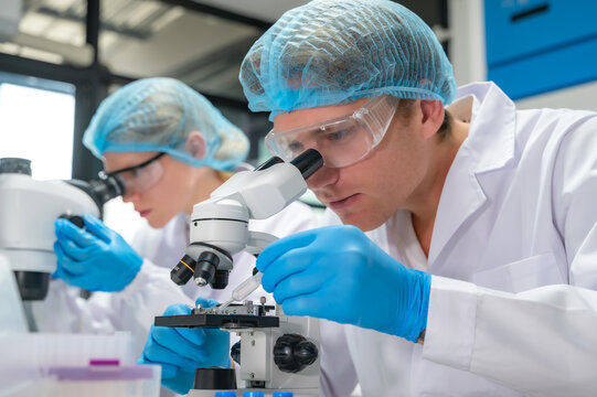 Caucasian male and female lab technician working with microscope in medical laboratory 