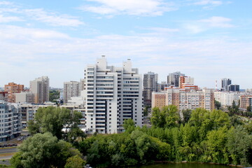 Fototapeta premium View of a city with houses and trees on a sunny hot summer day.