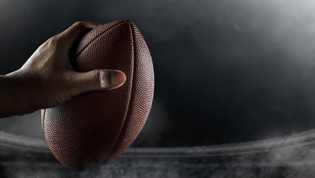 American football player holding the ball during the game in an American football stadium. Concept of sport - Powered by Adobe