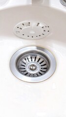 Close-up of a clean white kitchen sink drain