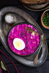 Cold lithuanian soup with beetroot, cucumber and egg on black wooden background vertical photo