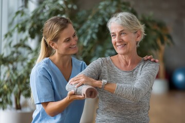 Physiotherapist assists senior patient with stretching exercises using resistance band in a bright clinic setting during morning therapy session