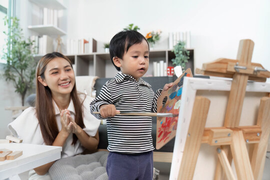 Encouraging creativity. Child painting while mother watches with pride.