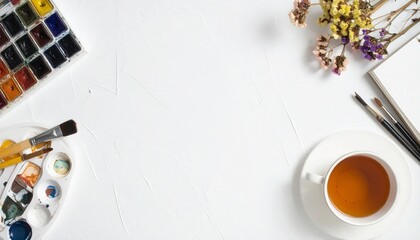 Creative artist's workspace invites inspiration with watercolor paints and brushes near tea