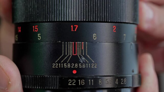 A detailed and technical mood is captured by a close-up of the aperture and focus rings on a vintage camera lens, highlighting the numerical markings and intricate design