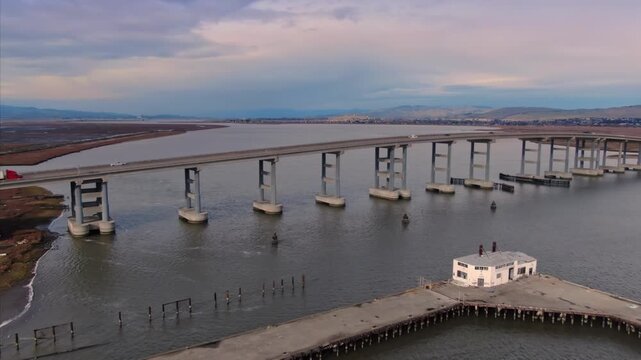 The Sears Point Rd Bridge spans the Napa River in Vallejo, California, USA. The image shows the bridge and an old pier with a building, highlighting infrastructure and transportation.