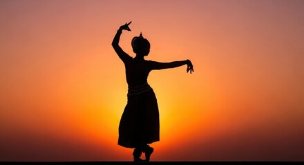 Fototapeta premium Graceful dancer performing a traditional pose against a vibrant sunset silhouette