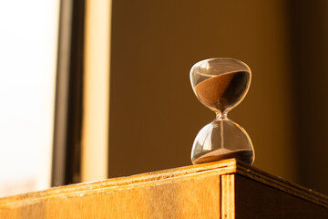 Hourglass on Wooden Cabinet in Warm Sunlight
