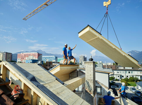 Workers standing on rooftop at construction site on sunny day