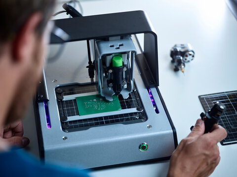 Engineer operating milling machine on circuit board in laboratory