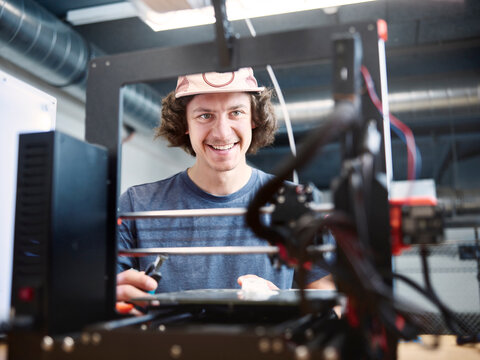 Smiling engineer looking at 3d printer at workshop