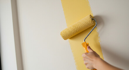 Person painting wall yellow with roller