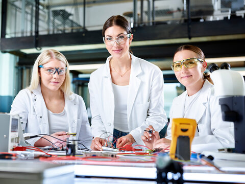 Smiling engineers with electronic work tools in laboratory