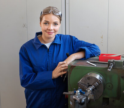 Smiling apprentice leaning on lathe at workshop