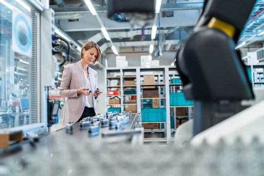 Businesswoman examining workpieces in a modern factory hall