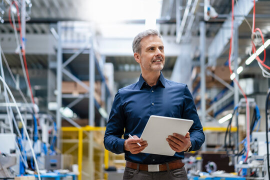 Mature businessman holding digital tablet in factory