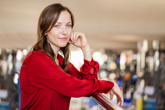Smiling woman wearing red shirt leaning on railing