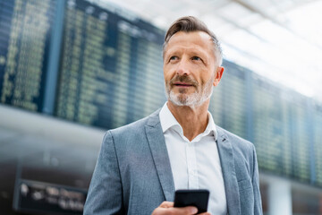 Contemplative mature businessman holding smart phone