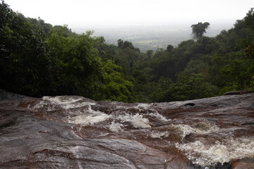 Dynamic flow of Tad Wimanthip Waterfall captured with fast currents rushing over layered rocks in a...