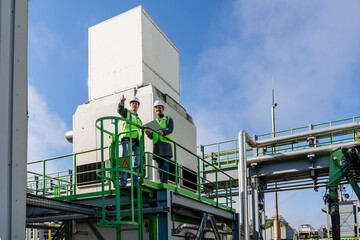 Engineer gesturing and discussing with colleague standing at recycling plant