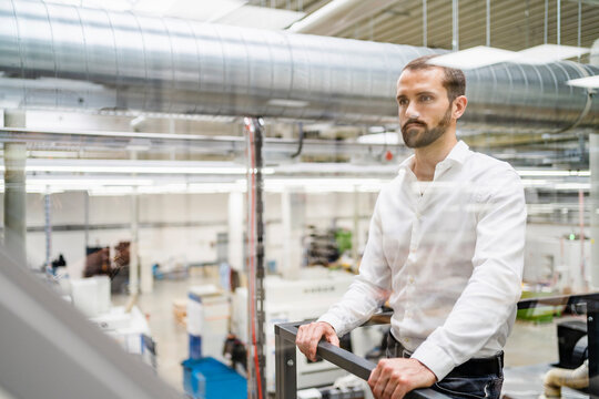 Thoughtful businessman standing near railing in industry